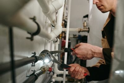Technician inspecting commercial plumbing pipes in Burbank